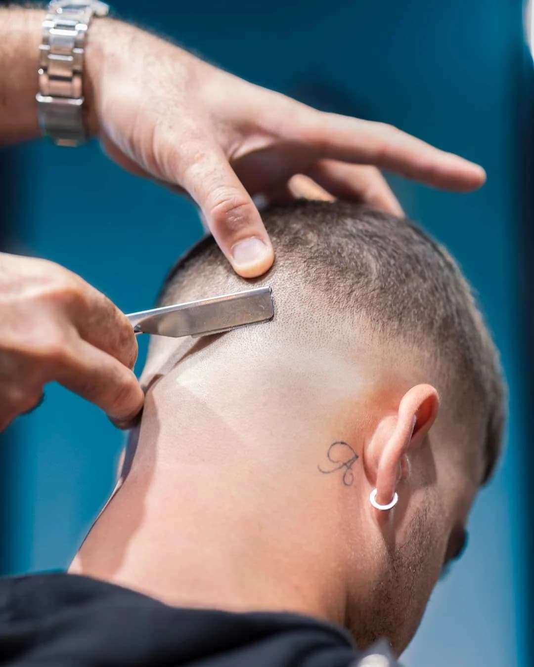 Barber using a straight razor to cut a sharp neckline, a skill built through formal school training
