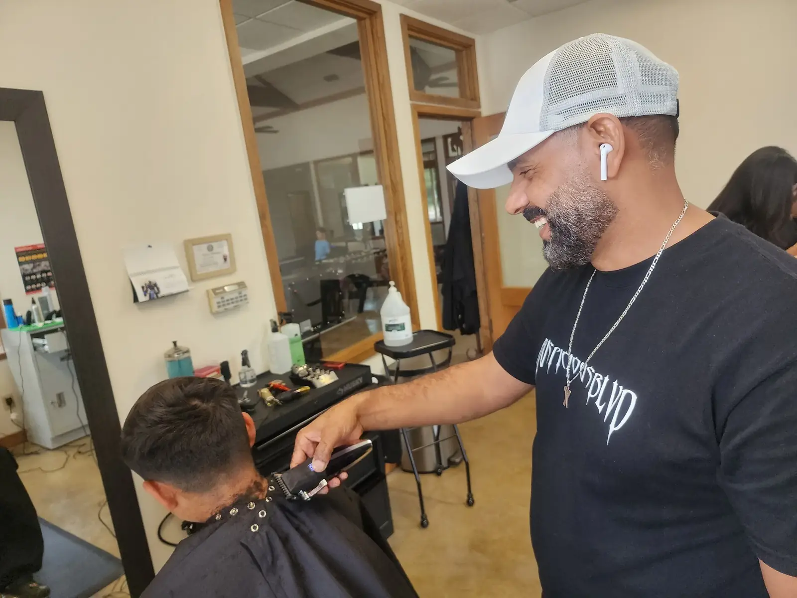 Instructor giving a student a haircut inside a licensed beauty school clinic