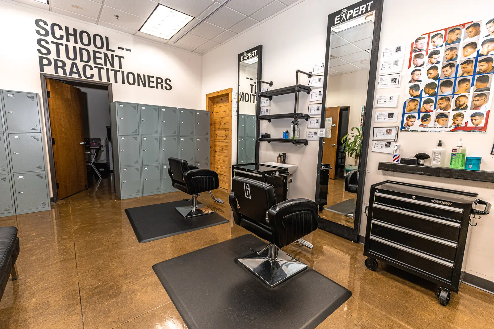 Barber stations in front of the School Student Practitioners wall at Expert Barber Beauty Academy