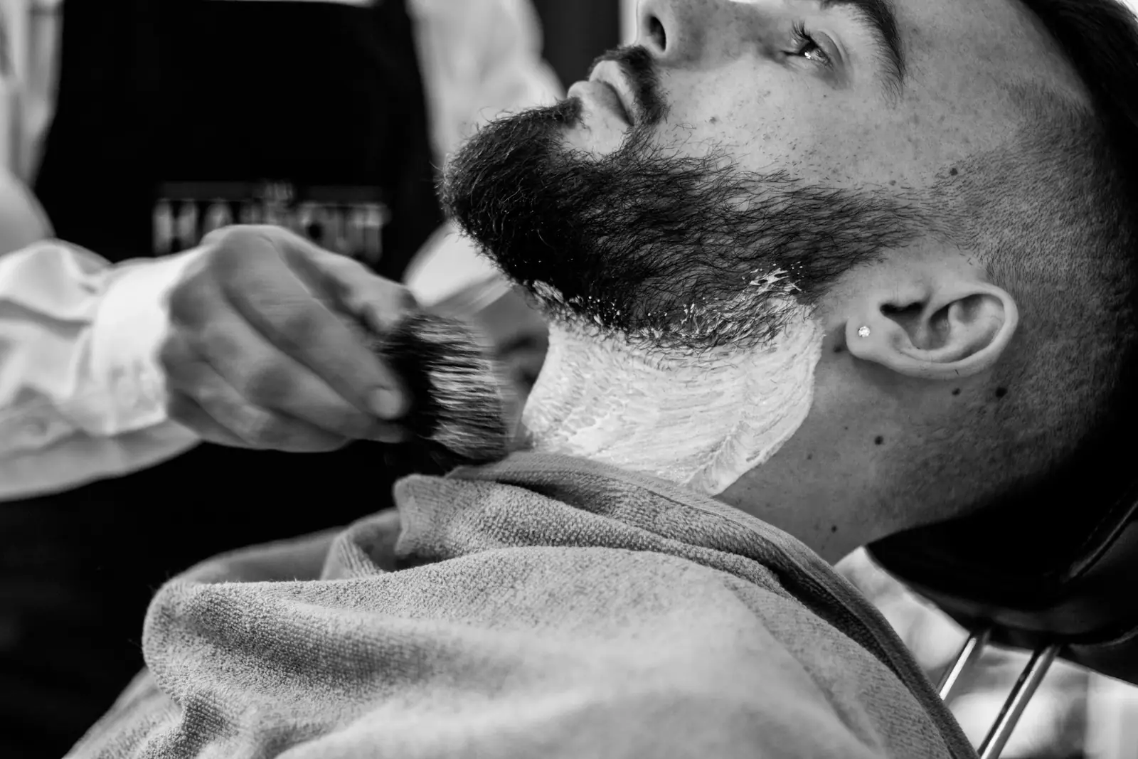Barber lathering a client's beard before a straight razor line-up