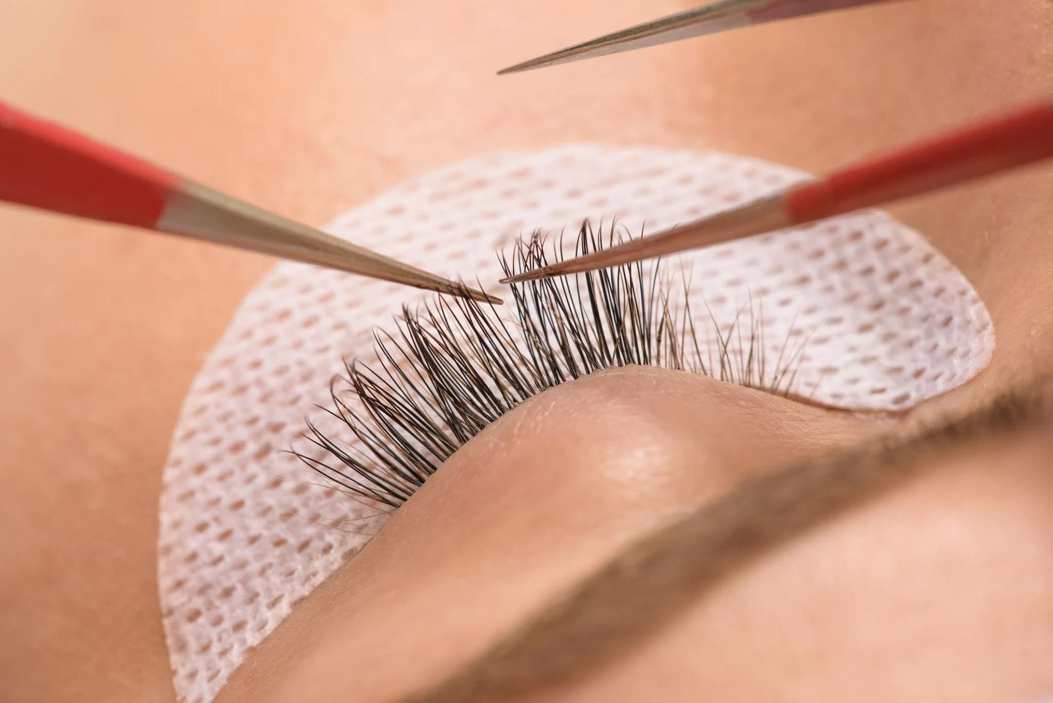Close-up of individual eyelash extensions being applied, the hands-on skill taught in the 320-hour Eyelash Extension certification